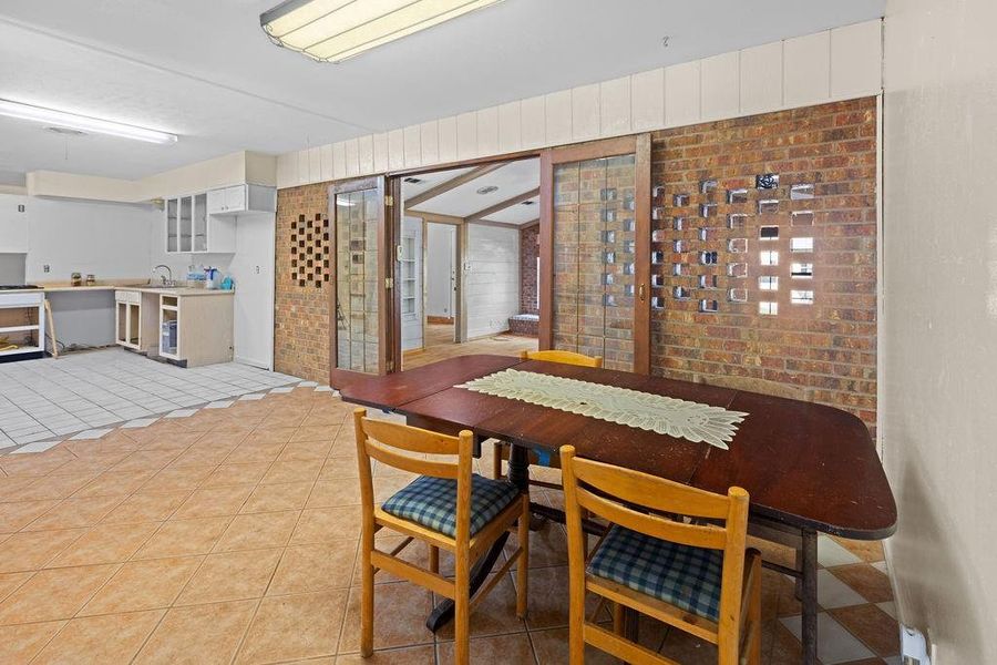 Dining area featuring light tile patterned floors and brick wall