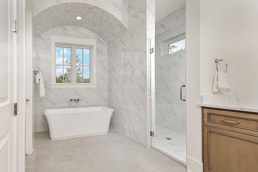 Breathtaking soaking garden tub is accentuated by spectacular arched ceiling with custom tiled accents and walk-in shower with frameless glass door.