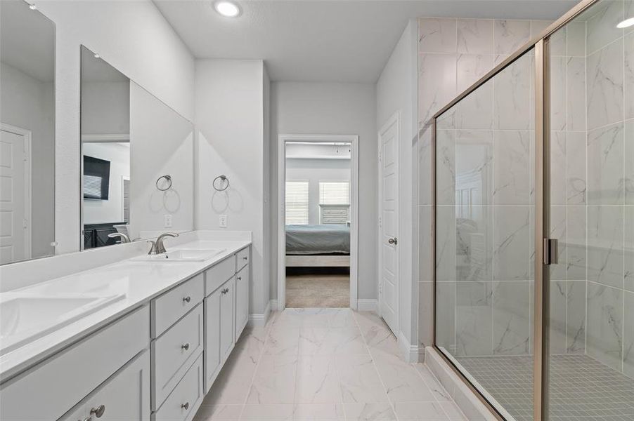 Bathroom with tile patterned floors, double vanity, and an enclosed shower