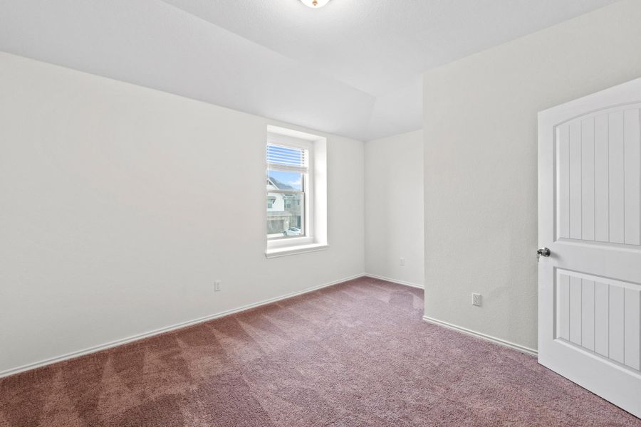 Inviting room featuring a single window, vaulted ceiling, and brown carpet