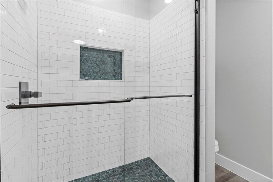 Bathroom with a shower with door, hardwood / wood-style flooring, and toilet