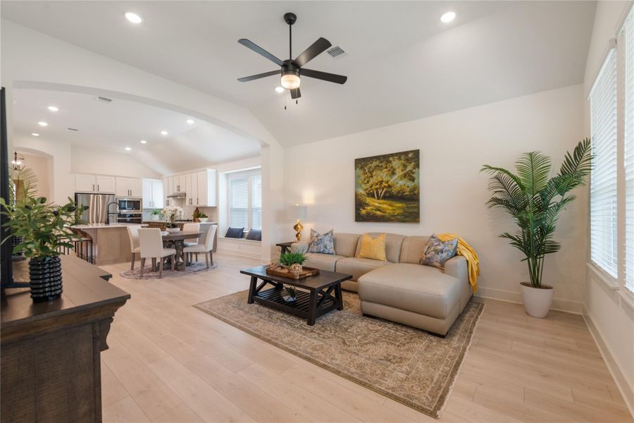 An open-concept living area boasts vaulted ceilings, seamlessly connecting to a modern kitchen and dining space. An open-concept living area boasts vaulted ceilings, seamlessly connecting to a modern kitchen and dining space.