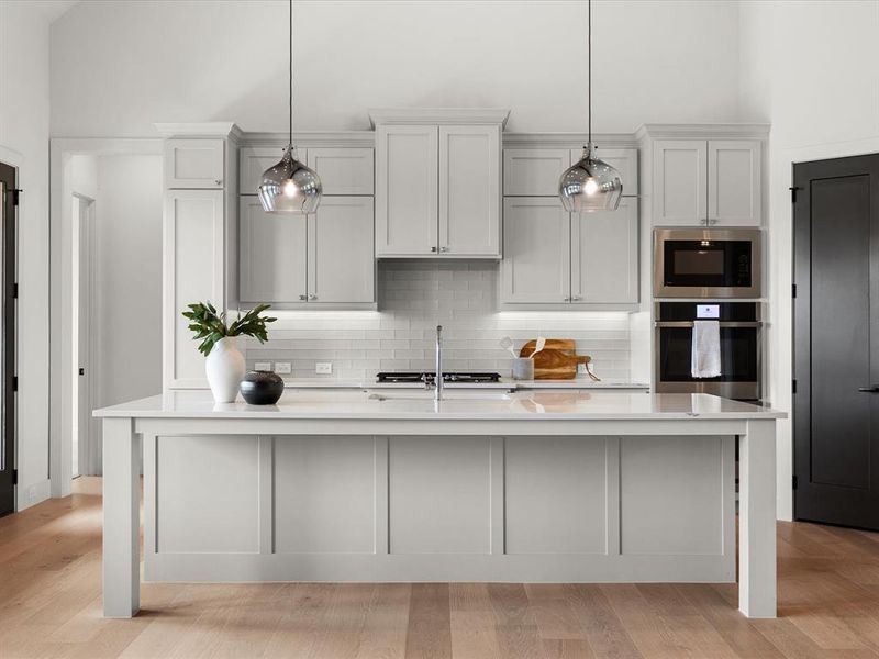 Kitchen with decorative backsplash, appliances with stainless steel finishes, a kitchen island with sink, light wood-style floors, and light stone countertops Kitchen with decorative backsplash, appliances with stainless steel finishes, a kitchen island with sink, light wood-style floors, and light stone countertops