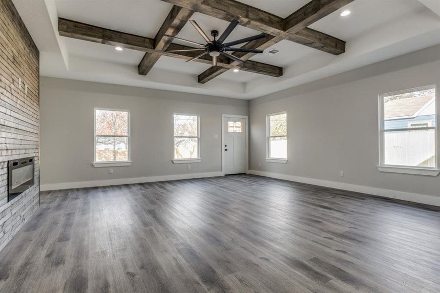 Unfurnished living room featuring beam ceiling, wood-type flooring, a fireplace, and coffered ceiling