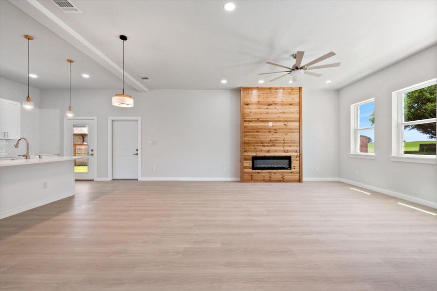 A well-lit living area features modern light fixtures, sleek flooring, and an attractive fireplace as its focal point.
