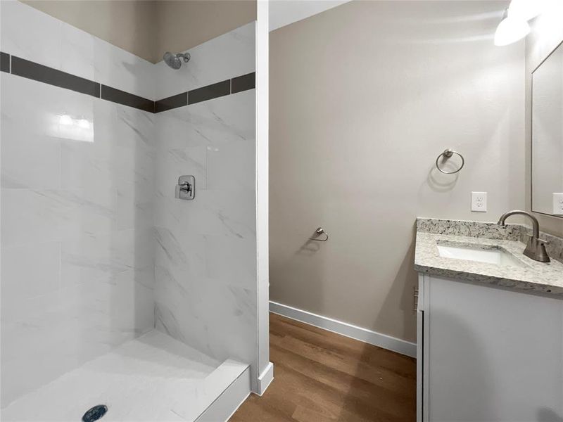 Bathroom with vanity, wood-type flooring, and tiled shower