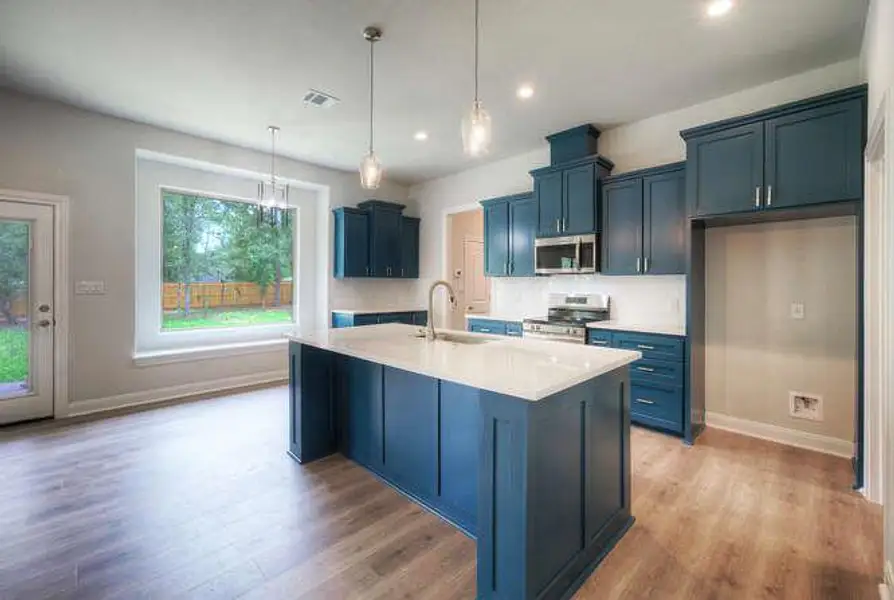 Kitchen with light wood-style floors, light countertops, stainless steel appliances, blue cabinets, and recessed lighting