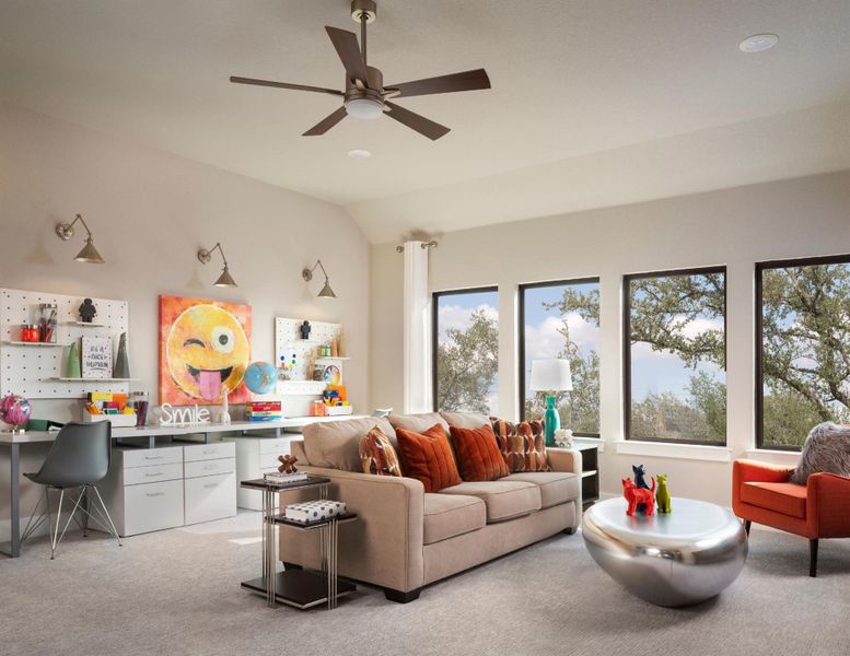 Living room with light carpet, ceiling fan, a desk, and vaulted ceiling