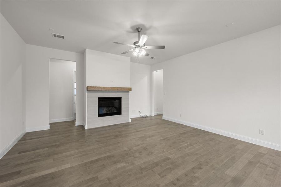 Unfurnished living room with a ceiling fan, wood finished floors, a fireplace, and baseboards Unfurnished living room with a ceiling fan, wood finished floors, a fireplace, and baseboards