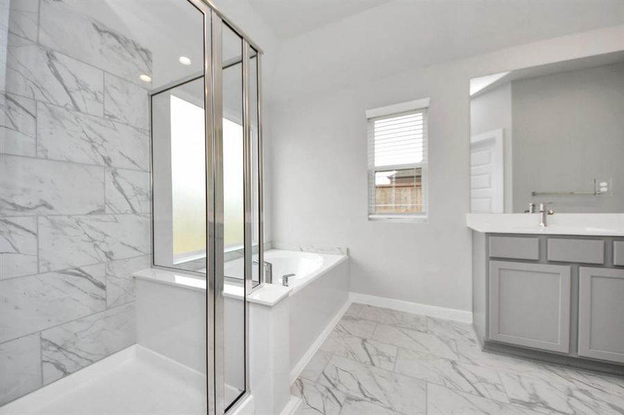 Escape to a spa-like oasis in this primary bathroom. Enjoy a walk-in shower with tile surround, a separate garden tub with custom detailing, and an elegant vanity featuring light countertops, modern hardware, and beautiful recessed lights. Experience luxury and relaxation in every detail!