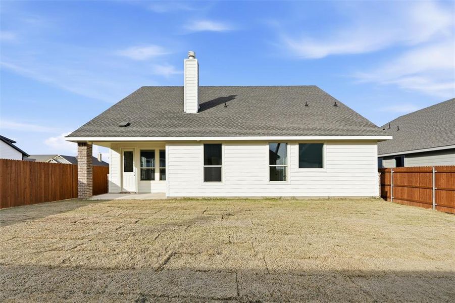 Back of property with a patio area, a chimney, a shingled roof, and a fenced backyard