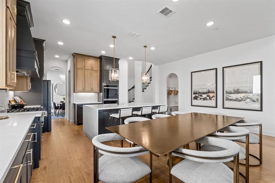 Dining space with arched walkways, recessed lighting, light wood finished floors, and stairway Dining space with arched walkways, recessed lighting, light wood finished floors, and stairway