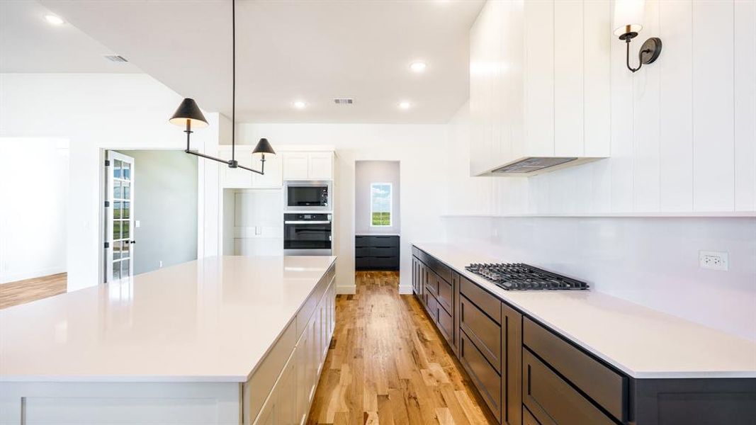 Kitchen with built in microwave, light wood-type flooring, a kitchen island, and black oven