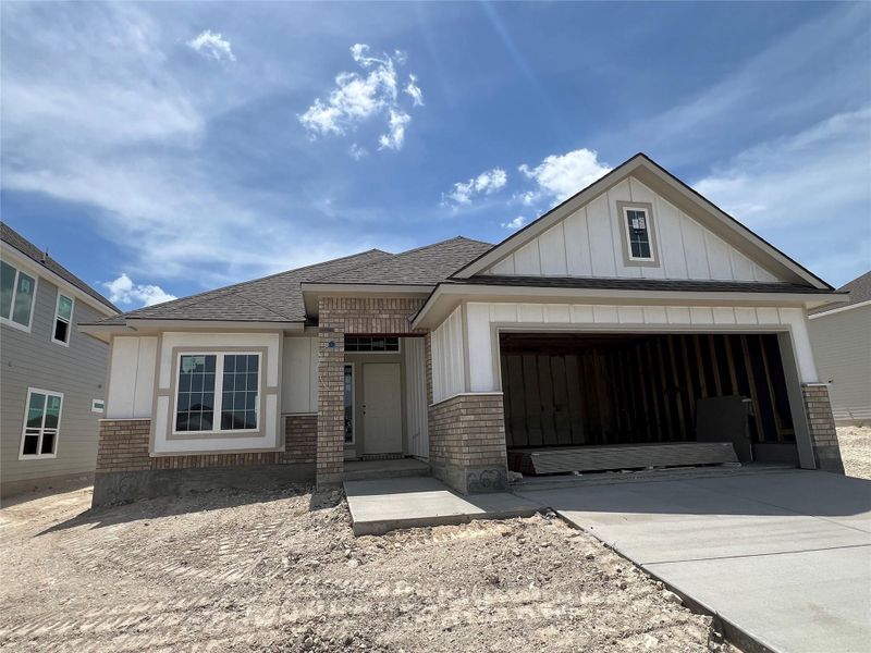View of front of property featuring brick siding, roof with shingles, concrete driveway, board and batten siding, and a garage