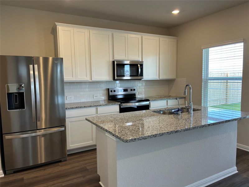 Kitchen with appliances with stainless steel finishes, decorative backsplash, light stone countertops, white cabinetry, and recessed lighting Kitchen with appliances with stainless steel finishes, decorative backsplash, light stone countertops, white cabinetry, and recessed lighting