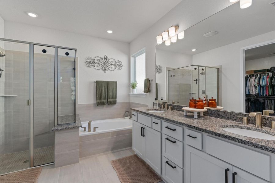Bathroom with double vanity, a spacious closet, a shower stall, a garden tub, and recessed lighting