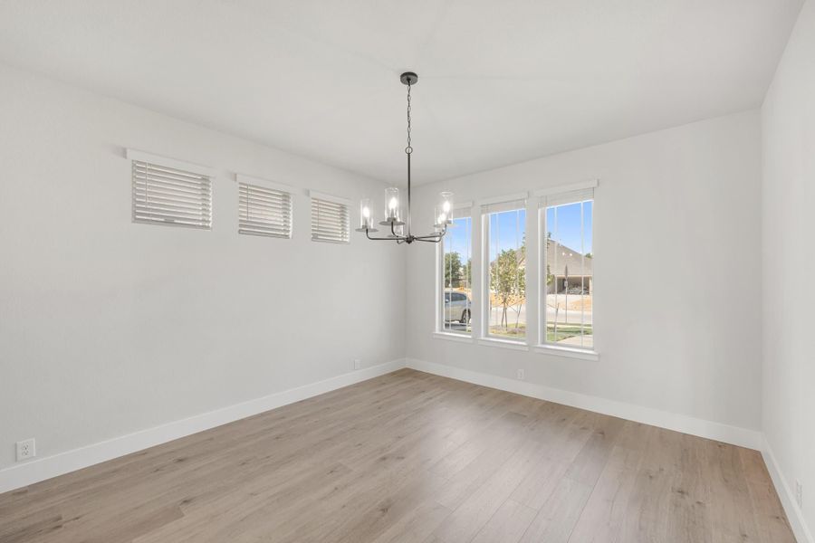 Empty dining room with light wood floors, chandelier, and large windows with white blinds Empty dining room with light wood floors, chandelier, and large windows with white blinds
