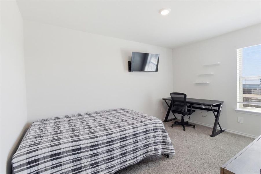 Bedroom featuring light carpet and a desk Bedroom featuring light carpet and a desk