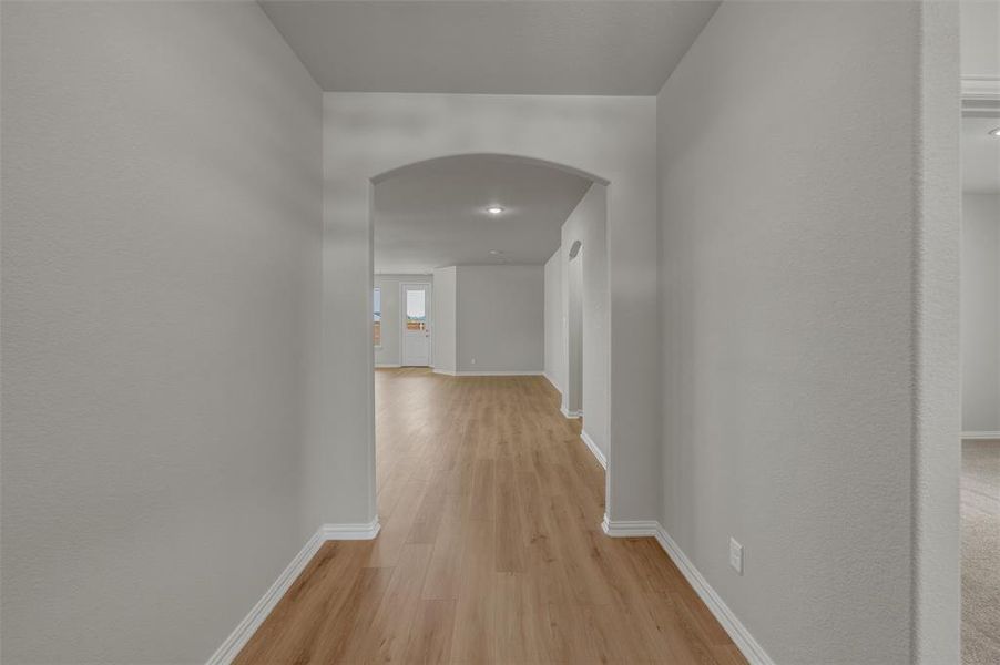 Archway entry to a main living area featuring light wood-finish flooring and light gray painted walls Archway entry to a main living area featuring light wood-finish flooring and light gray painted walls