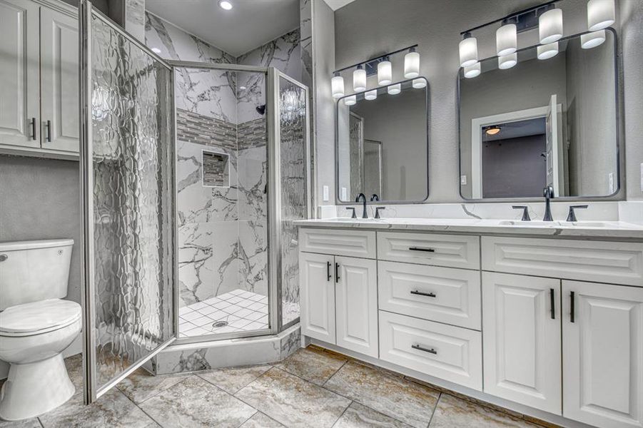 Full bathroom featuring double vanity and a marble finish shower