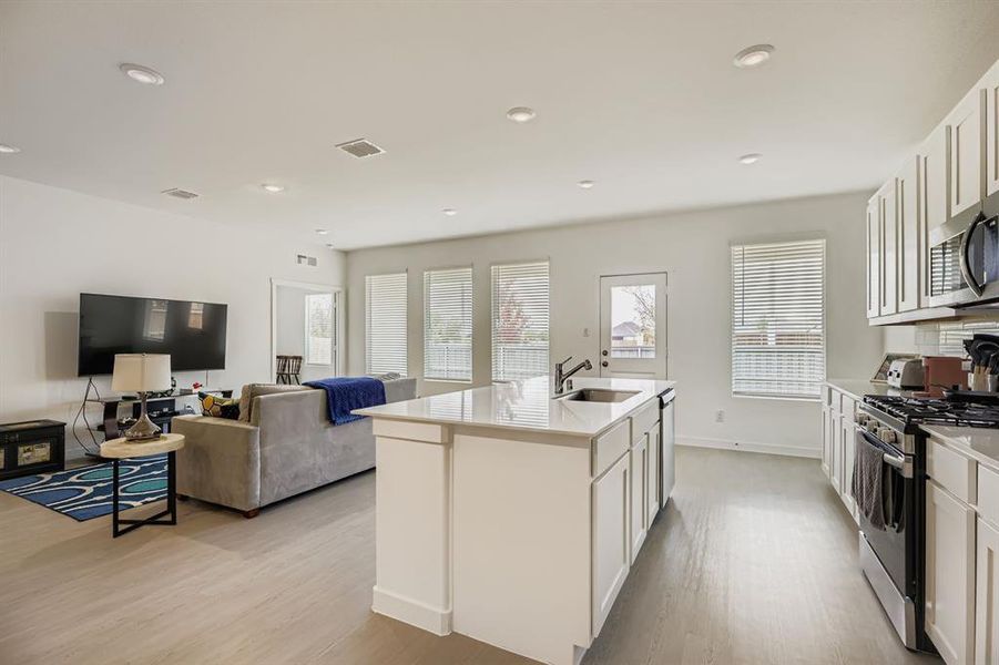 Kitchen featuring white cabinetry, appliances with stainless steel finishes, open floor plan, light wood-style floors, and recessed lighting