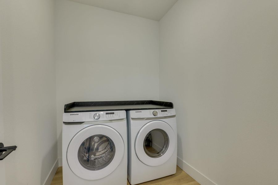 Dedicated laundry area featuring a front-loading washer and dryer, with a counter space above