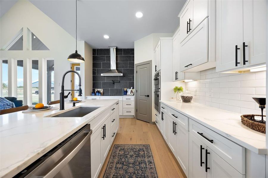 Kitchen featuring white cabinetry, decorative backsplash, sink, and light wood-type flooring