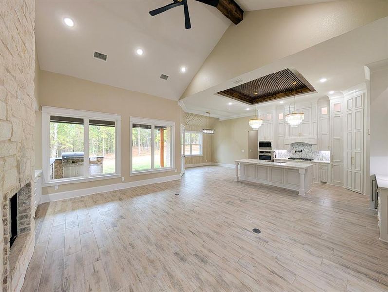 Unfurnished living room with light wood-type flooring, a fireplace, beam ceiling, healthy amount of natural light, and high vaulted ceiling