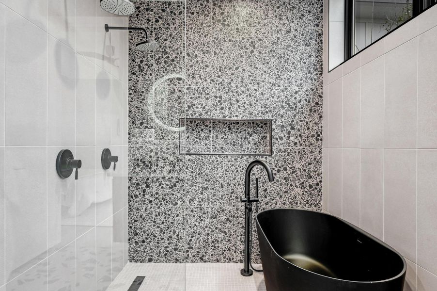 Full bathroom with a stall shower, a freestanding tub, and tile walls