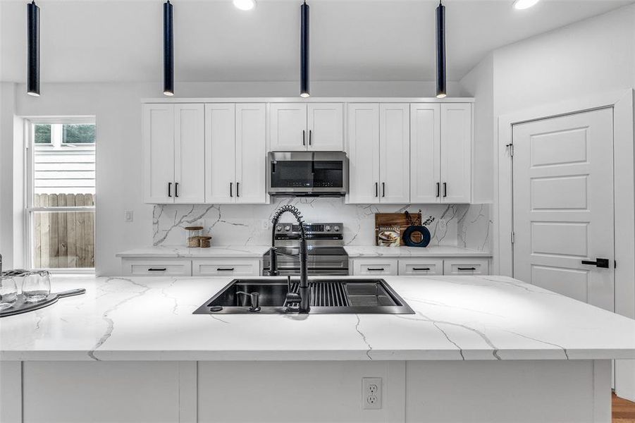 Kitchen with backsplash, white cabinetry, light stone counters, beam ceiling, and recessed lighting Kitchen with backsplash, white cabinetry, light stone counters, beam ceiling, and recessed lighting