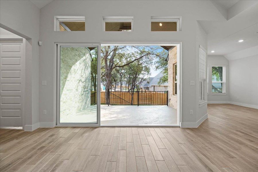 Doorway to outside with lofted ceiling, wood finished floors, and recessed lighting