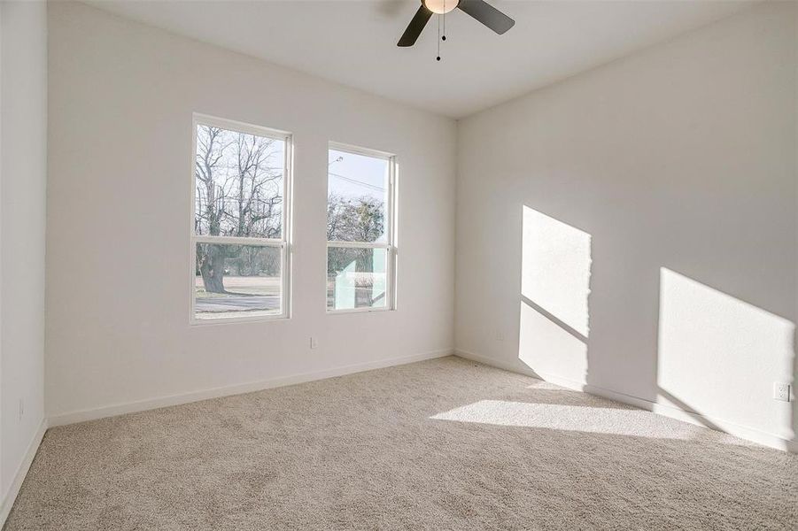 Empty room with ceiling fan and light colored carpet