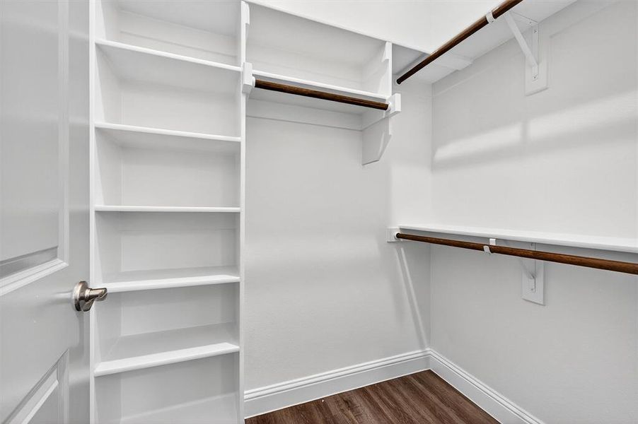 Walk in closet with dark wood-style flooring