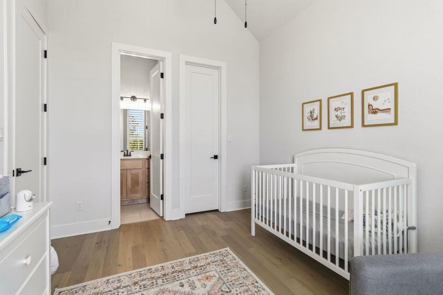 Hardwood floors complement the vaulted ceilings in this serene nursery, offering direct access to an attached bathroom.