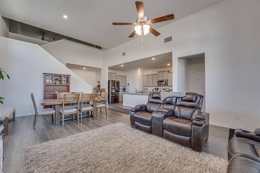 Living room with dark wood-style floors, recessed lighting, a ceiling fan, and high vaulted ceiling