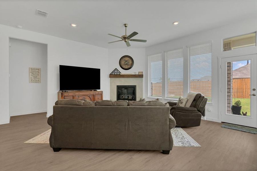 Living room with recessed lighting, light wood finished floors, a glass covered fireplace, and ceiling fan