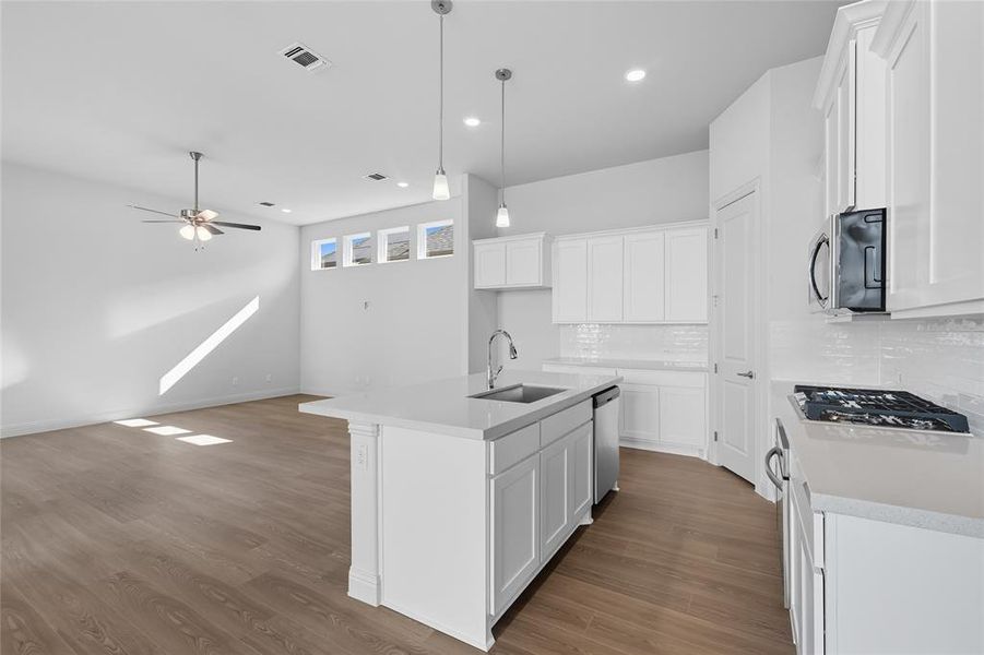 Kitchen featuring white cabinetry, a kitchen island with sink, light stone countertops, tasteful backsplash, and recessed lighting