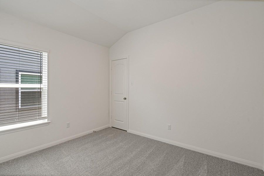Plush carpeting and vaulted ceilings enhance this serene bedroom space.