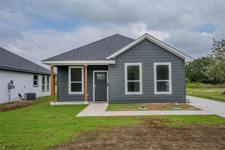 View of front of house featuring cooling unit and a front yard