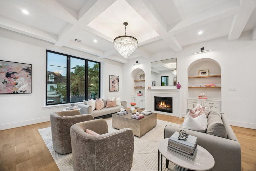 A refined yet welcoming living room that blends classic architectural details with modern comfort. Painted Boxed Beamed ceiling, Arched built-ins and a centered cast stone fireplace provide timeless structure, while soft lighting add warmth and sofistication. Large windows flood the space with natural light, making it ideal for both relaxing and entertaining.