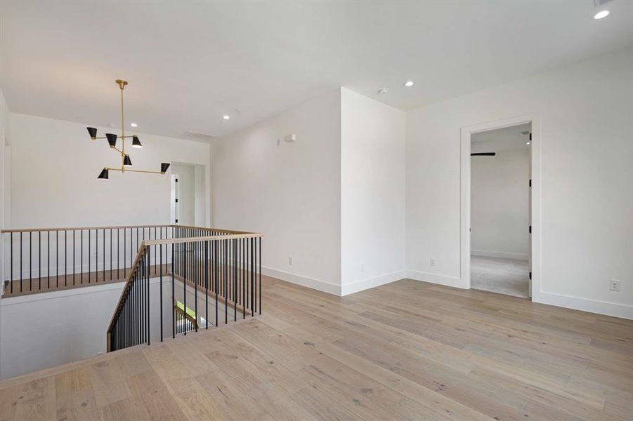 Spare room with light wood-type flooring and a notable chandelier