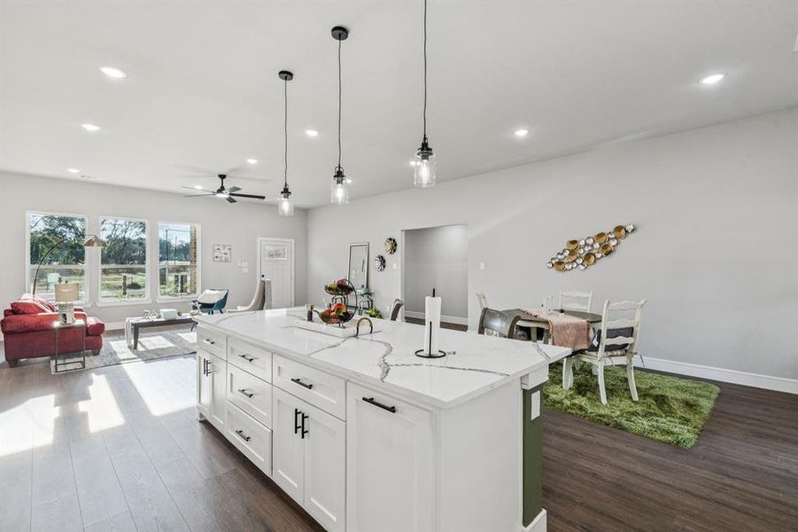 Kitchen with light stone counters, open floor plan, hanging light fixtures, recessed lighting, and ceiling fan
