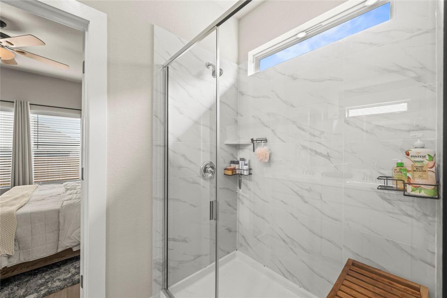 Marble-look tile lines the shower, offering a pristine and easy-to-maintain space. Marble-look tile lines the shower, offering a pristine and easy-to-maintain space.