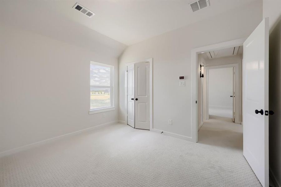 Light-filled room featuring textured carpet flooring, a single window, and white interior doors with black hardware