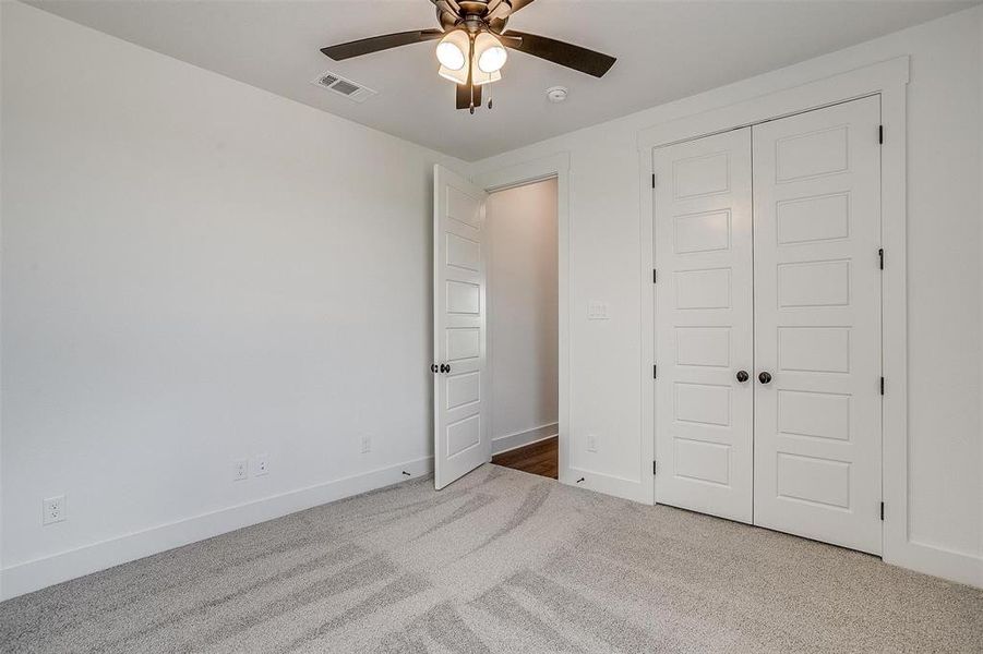 Unfurnished bedroom featuring light carpet, a closet, and ceiling fan