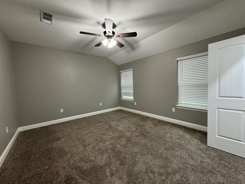 Spare room with dark colored carpet, a textured ceiling, ceiling fan, and lofted ceiling