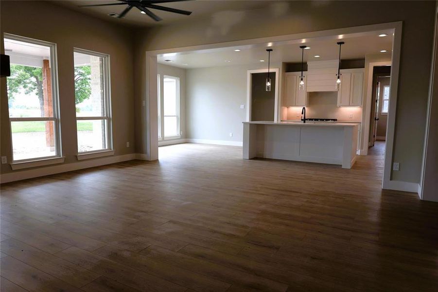 Unfurnished living room with sink, dark hardwood / wood-style flooring, a wealth of natural light, and ceiling fan