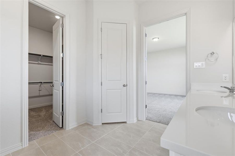 Full bathroom featuring light colored carpet, double vanity, a spacious closet, and light tile patterned flooring