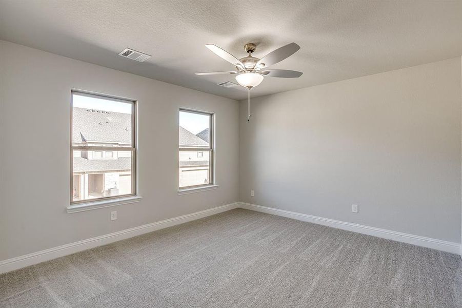Empty room with light colored carpet, a ceiling fan, and a textured ceiling