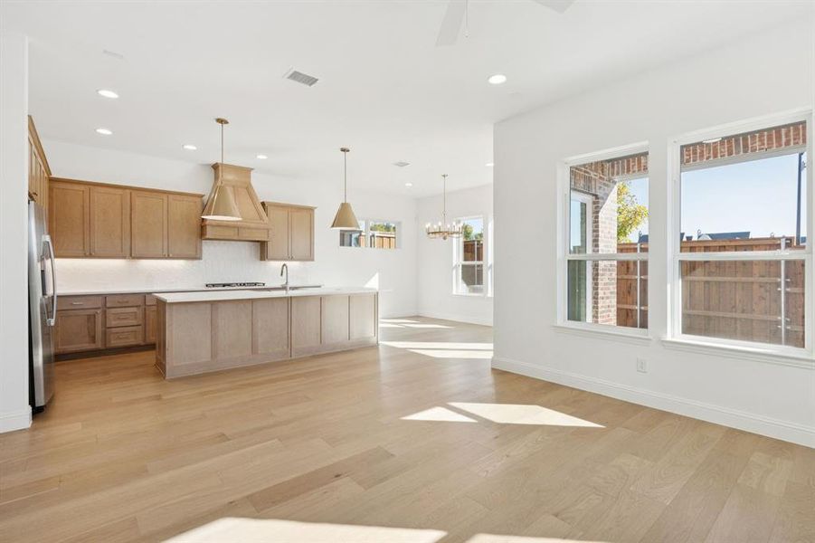 Kitchen with light brown cabinets, hanging light fixtures, light wood finished floors, appliances with stainless steel finishes, and recessed lighting